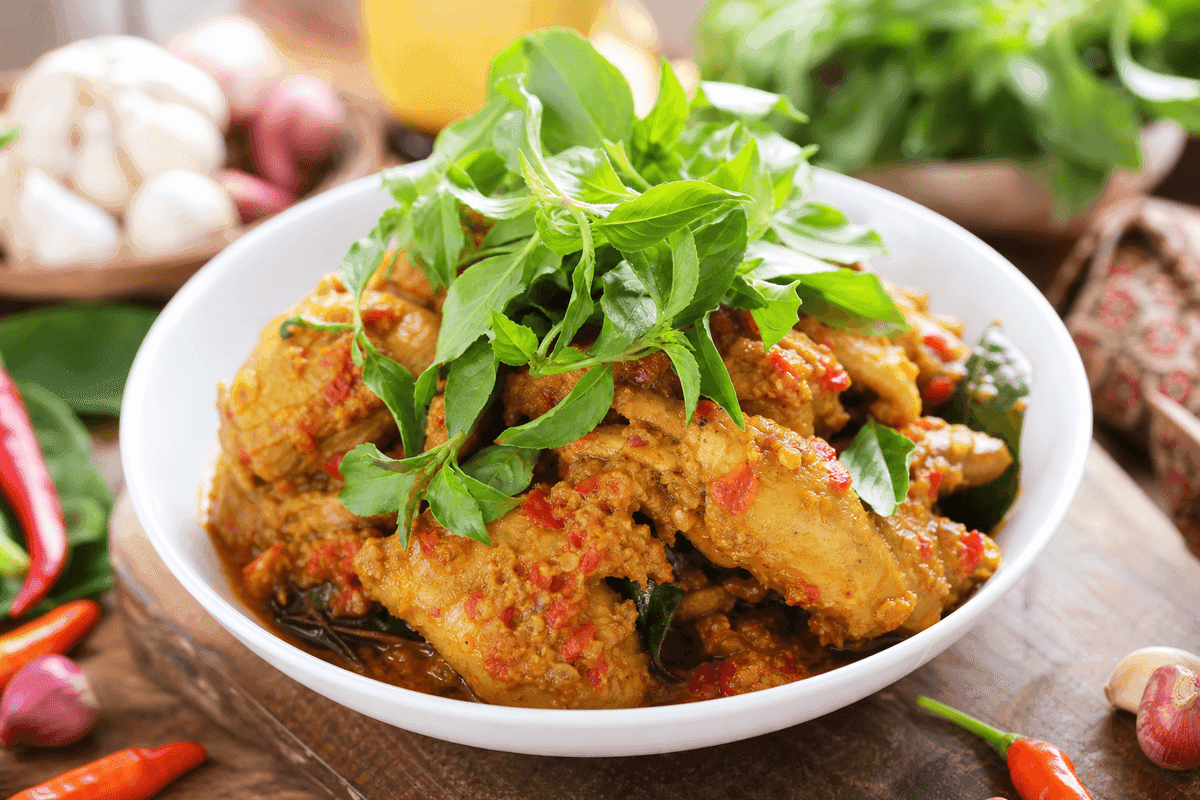 Ayam rica-rica dengan taburan daun kemangi segar melimpah di atas mangkuk saji putih